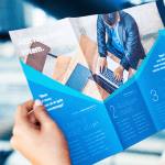 Tri-fold brochure being held open, displaying blue-themed design with images and text sections.